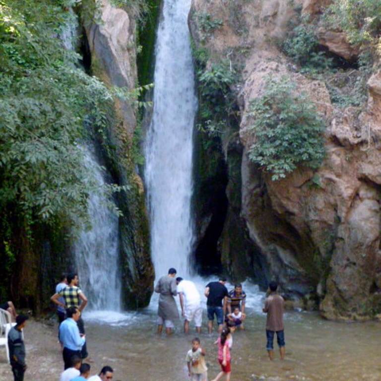 adults and children play under a waterfall