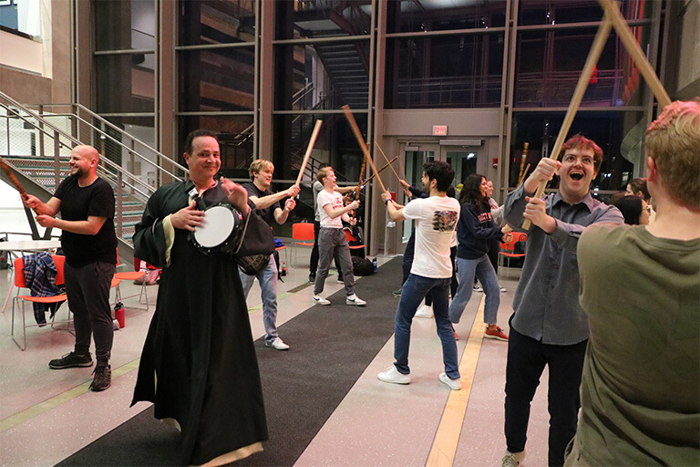 Students hold wooden swords while some play instruments.