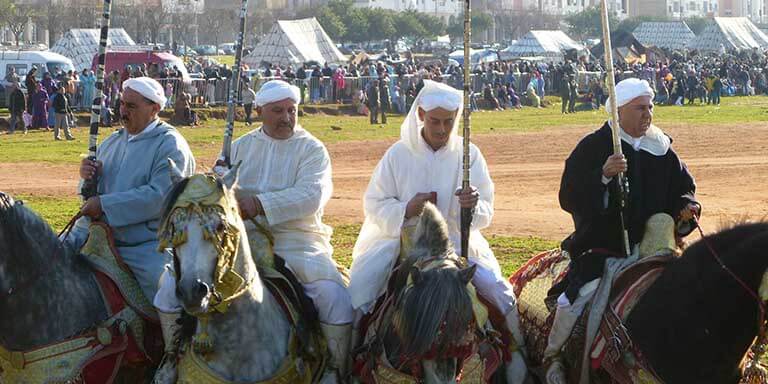 four men dressed in historic arabic dress on horses