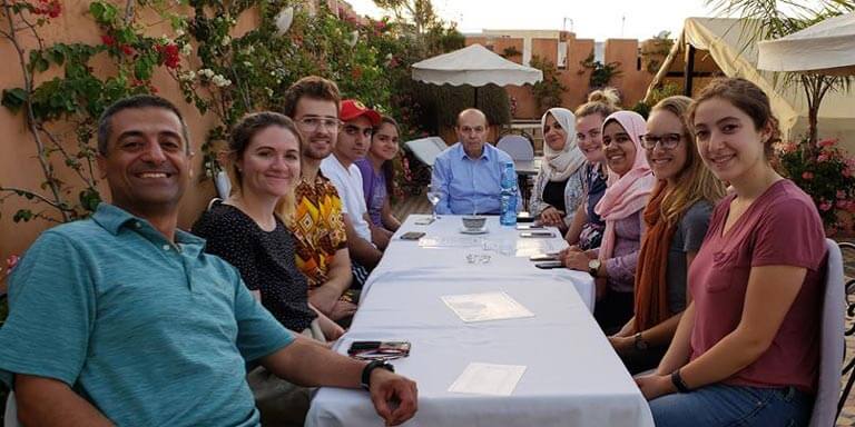class photo at a dinner table outdoors