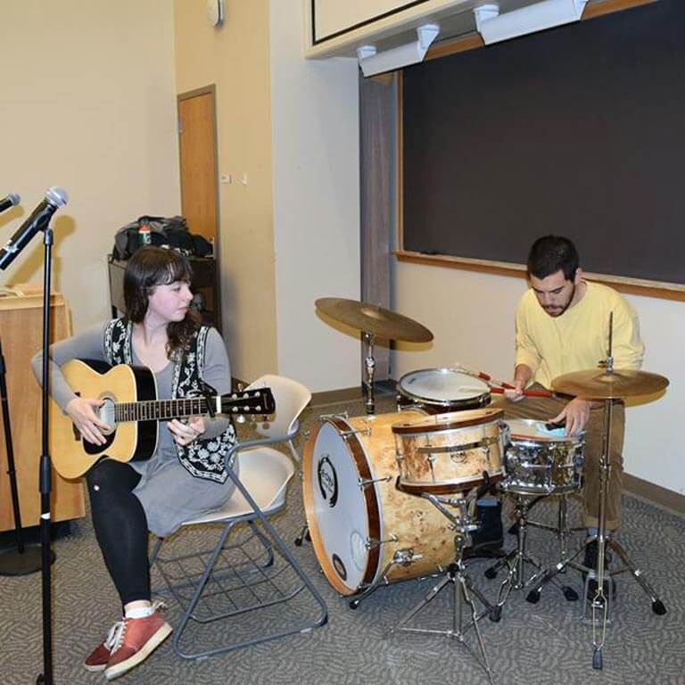woman playing guitar and man playing drums