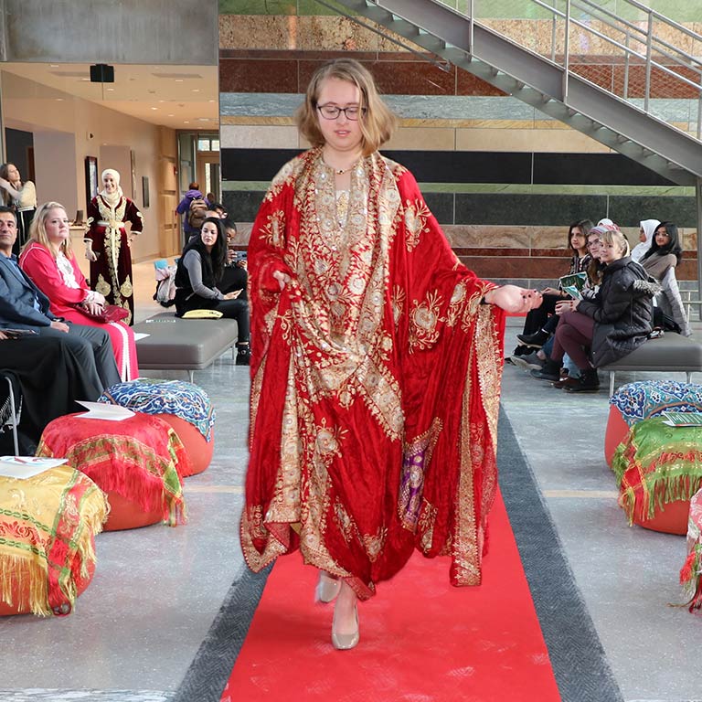 Woman walks down fashion catwalk wearing Arabic style dress