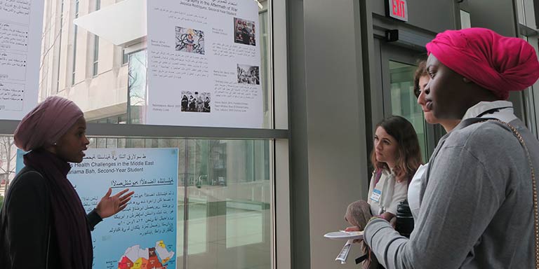 female student talking to others about her research poster