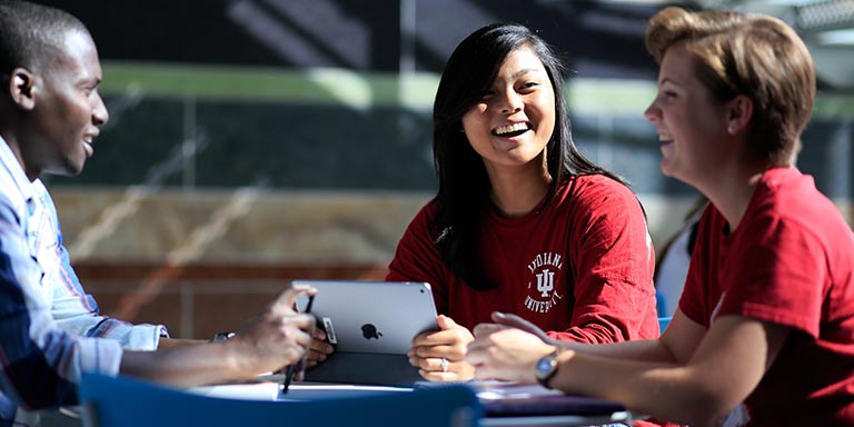 three students sitting at a table laughing
